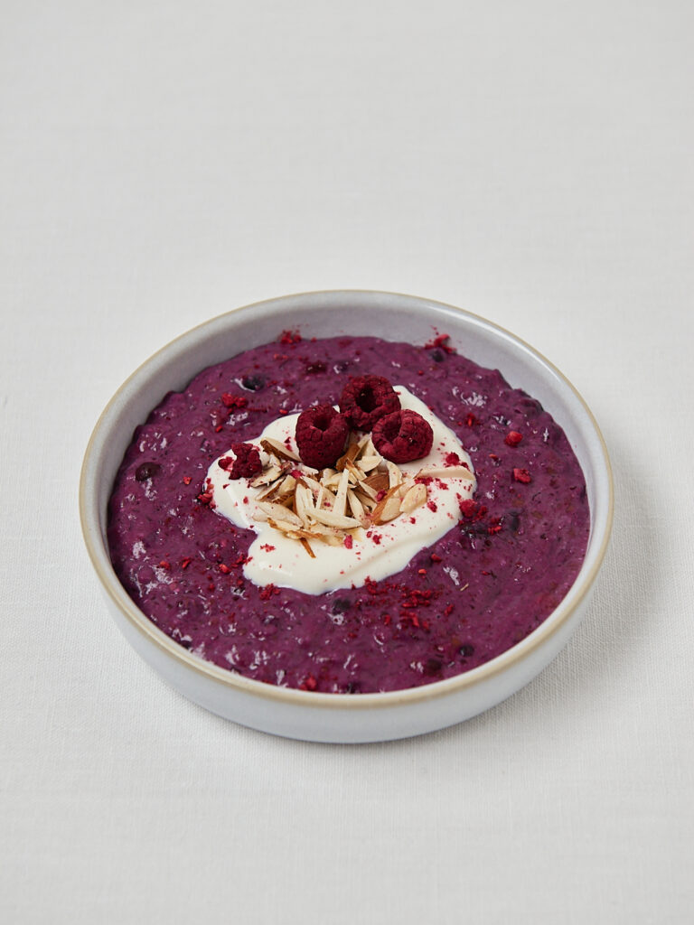 Cremiges lila Porridge mit Joghurt-Swirl, Himbeeren und Mandelbl&auml;ttchen &ndash; Draufsicht