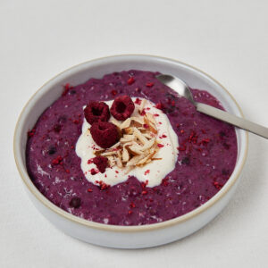 Low Carb Chocolate Almond Porridge in runder Schale mit Himbeere und L&ouml;ffel &ndash; Draufsicht