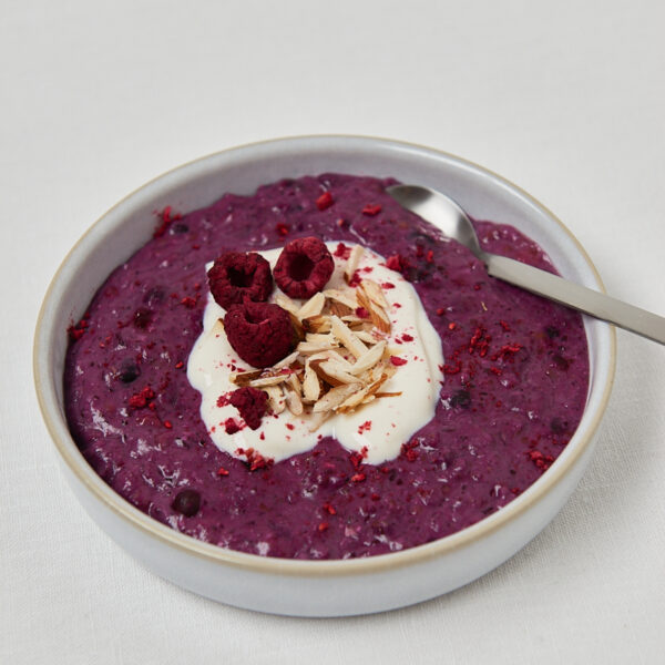 Low Carb Chocolate Almond Porridge in runder Schale mit Himbeere und Löffel – Draufsicht