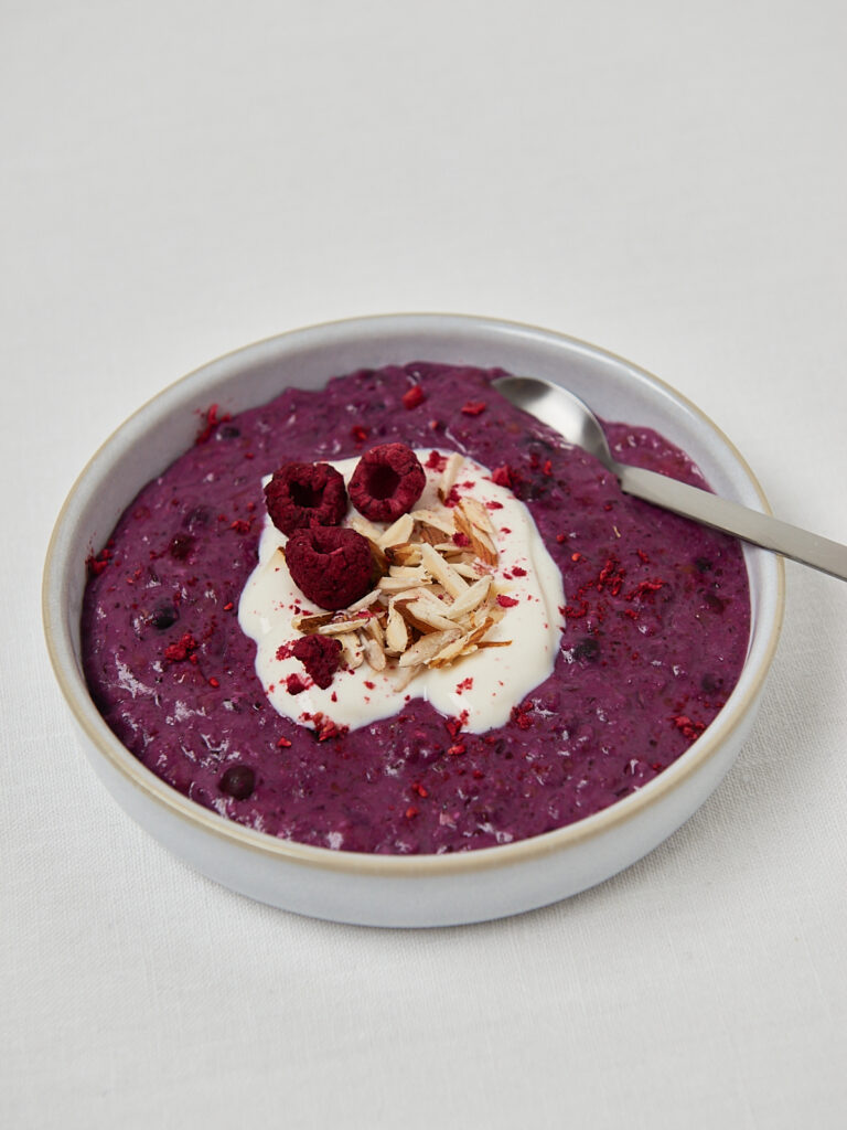 Low Carb Chocolate Almond Porridge in runder Schale mit Himbeere und L&ouml;ffel &ndash; Draufsicht