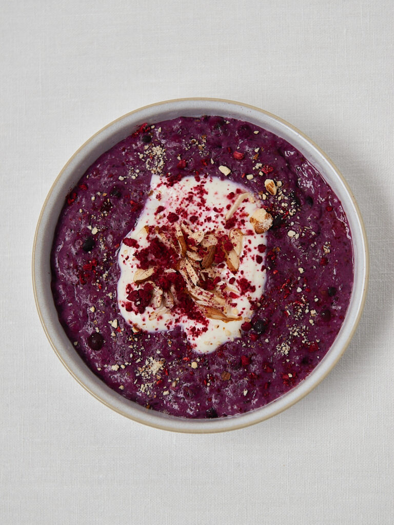 Low Carb Porridge in wei&szlig;er Bowl mit Joghurt-Topping, Mandelbl&auml;ttchen, Chiasamen und gefriergetrockneten Himbeeren &ndash; Draufsicht