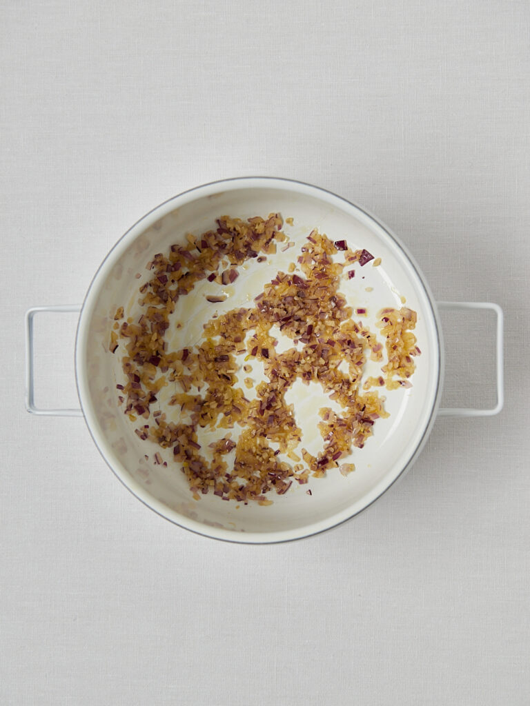 Rotes Linsen Dal in weißem Topf mit Kokosmilch-Swirl und gerösteten Nüssen, Draufsicht