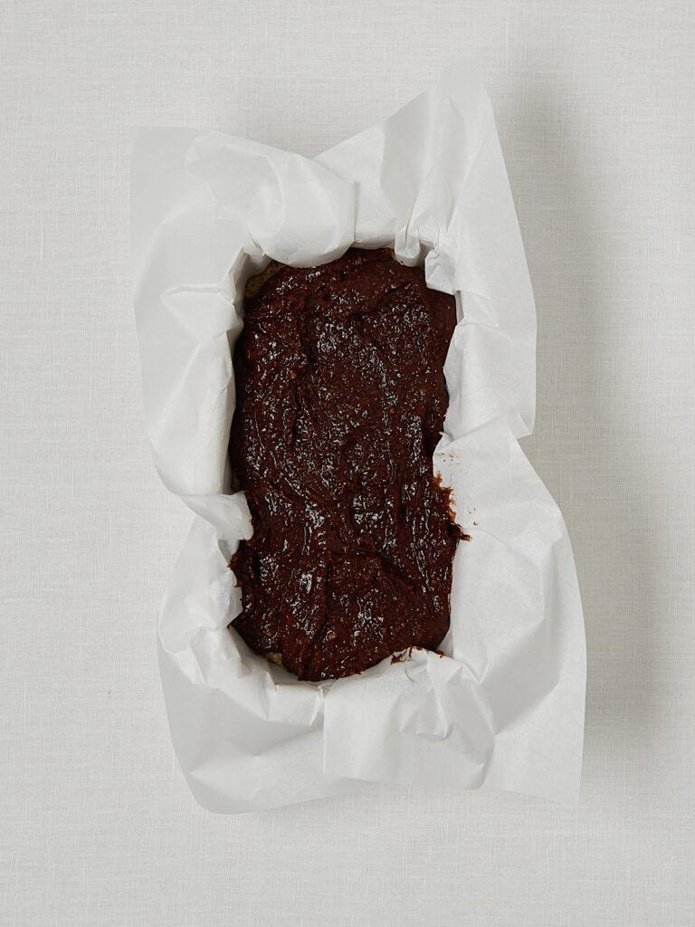 Dunkler Nusskuchen Teig in Kastenform mit Backpapier, gleichmäßig verteilt, Backschritt