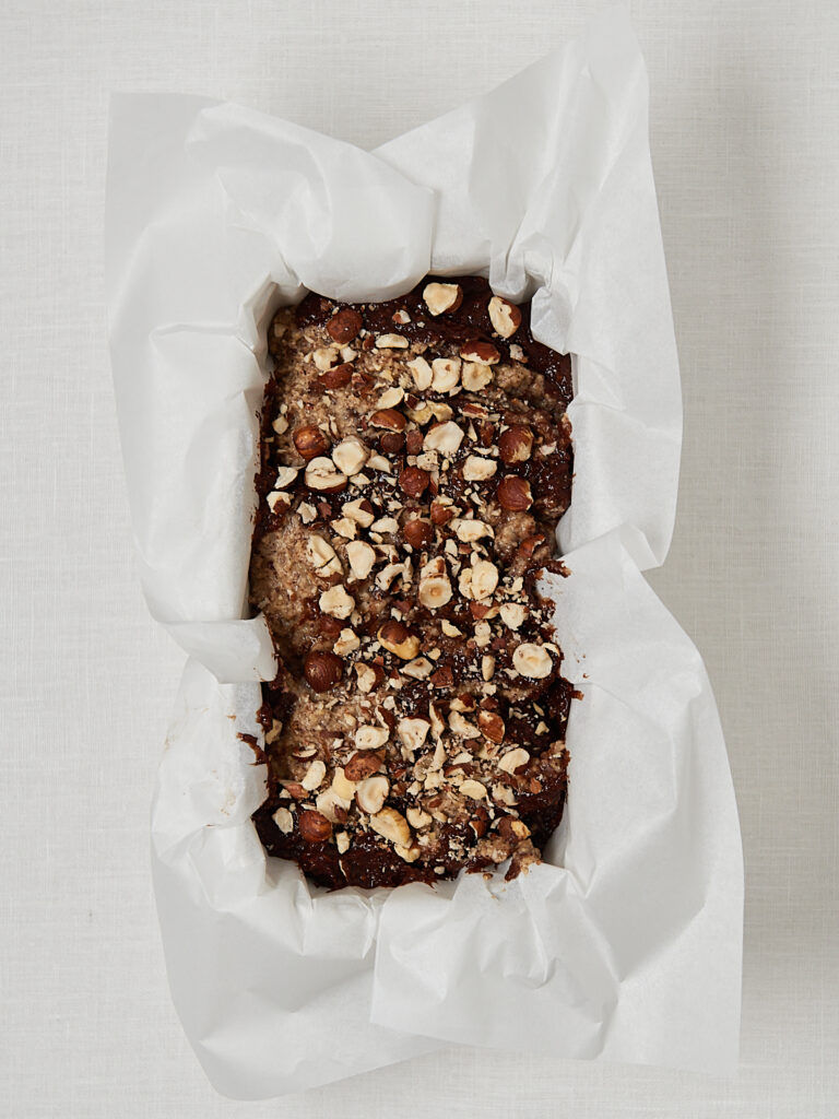 Low Carb Nusskuchen Teig mit Haselnuss-Topping in mit Backpapier ausgelegter Kastenform, backfertig