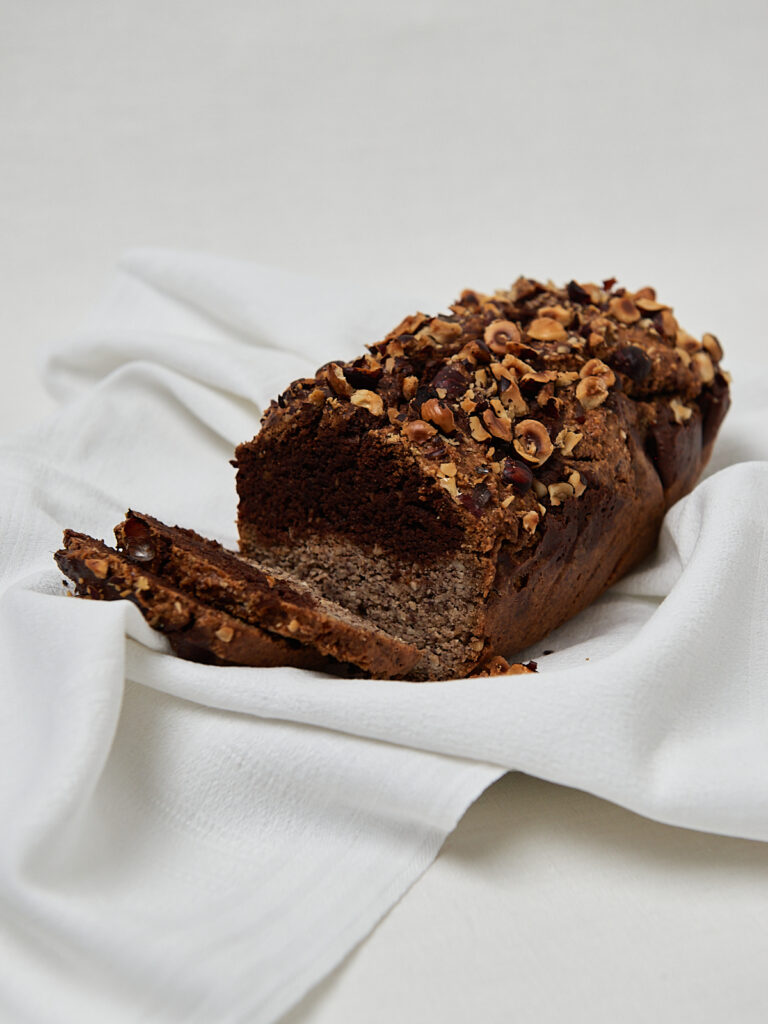 Low Carb Haselnusskuchen in Kastenform auf Leinentuch, Schokoswirl sichtbar beim Anschneiden