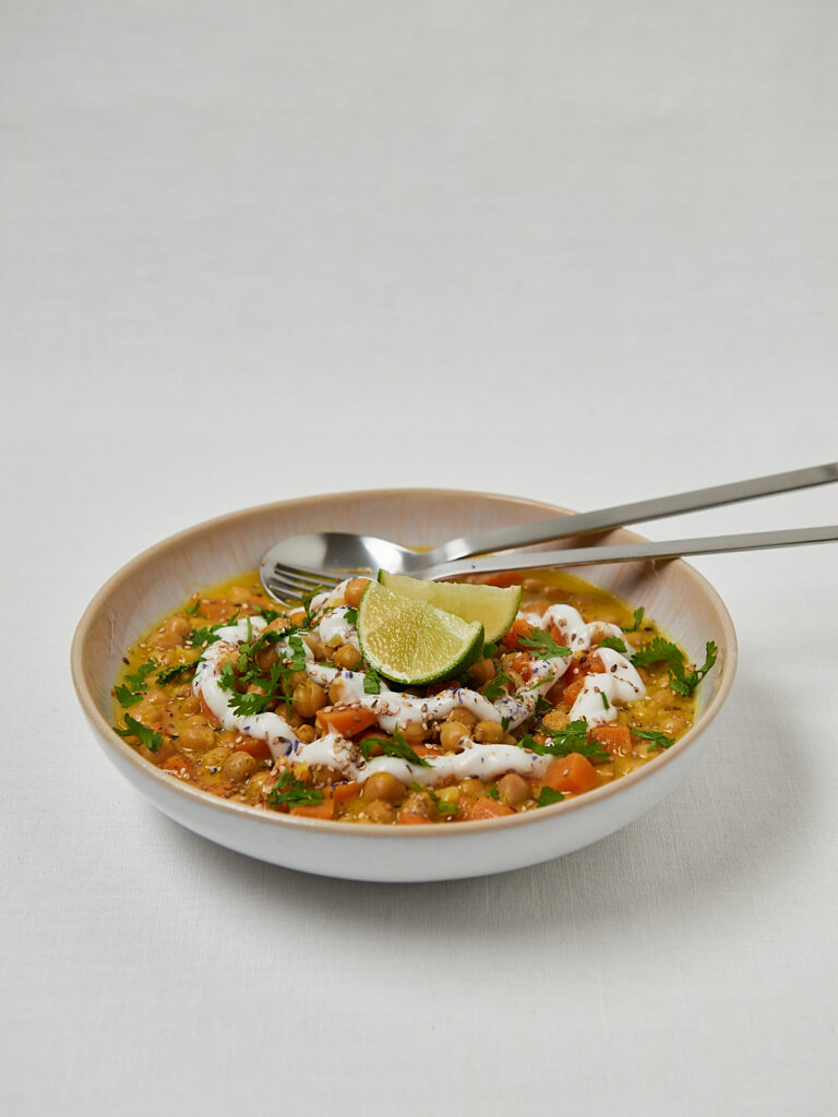 Linsensuppe mit Kokosjoghurt, Avocado und Limette in flacher Schale &ndash; seitliche Aufnahme