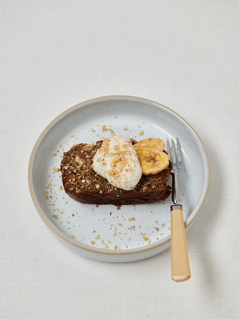 Protein Banana Bread mit frischer Banane als Topping – Draufsicht auf grauem Teller