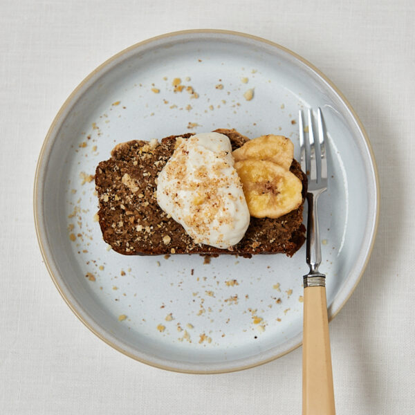 Protein Banana Bread mit frischer Banane als Topping – Draufsicht auf grauem Teller