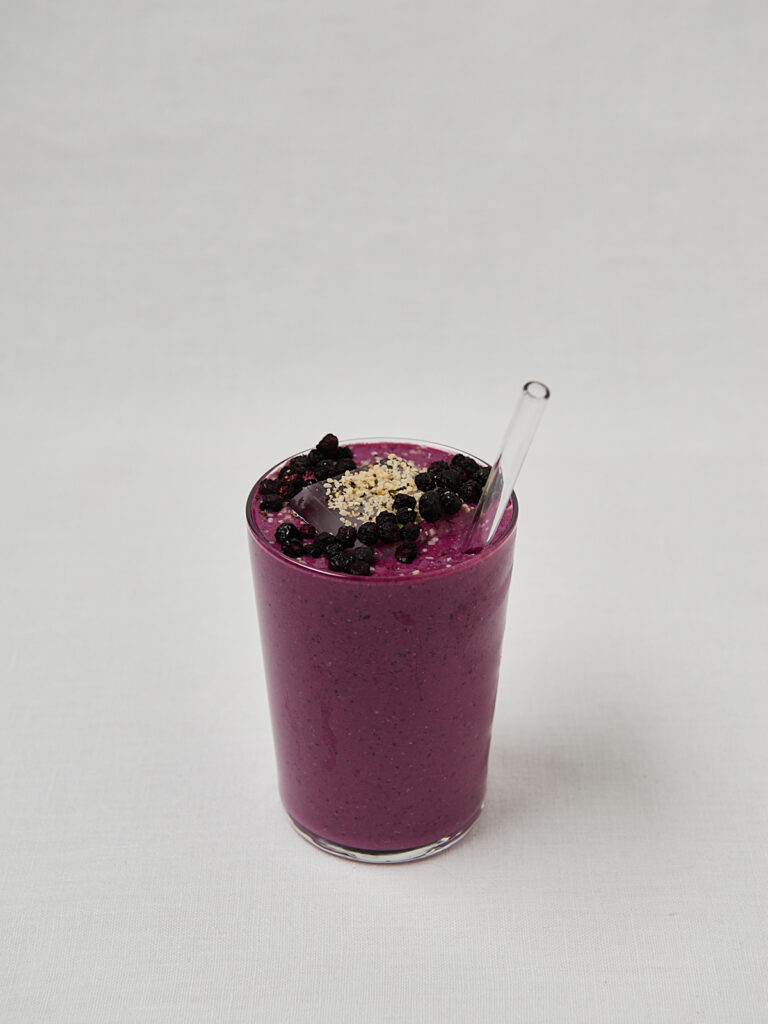 Cremiger lila Beeren-Shake mit Metallstrohhalm und Samen-Topping &ndash; Hochformat