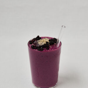 Super Power Shake im hohen Glas mit Hanfsamen und Beeren-Topping &ndash; seitliche Ansicht auf wei&szlig;em Hintergrund