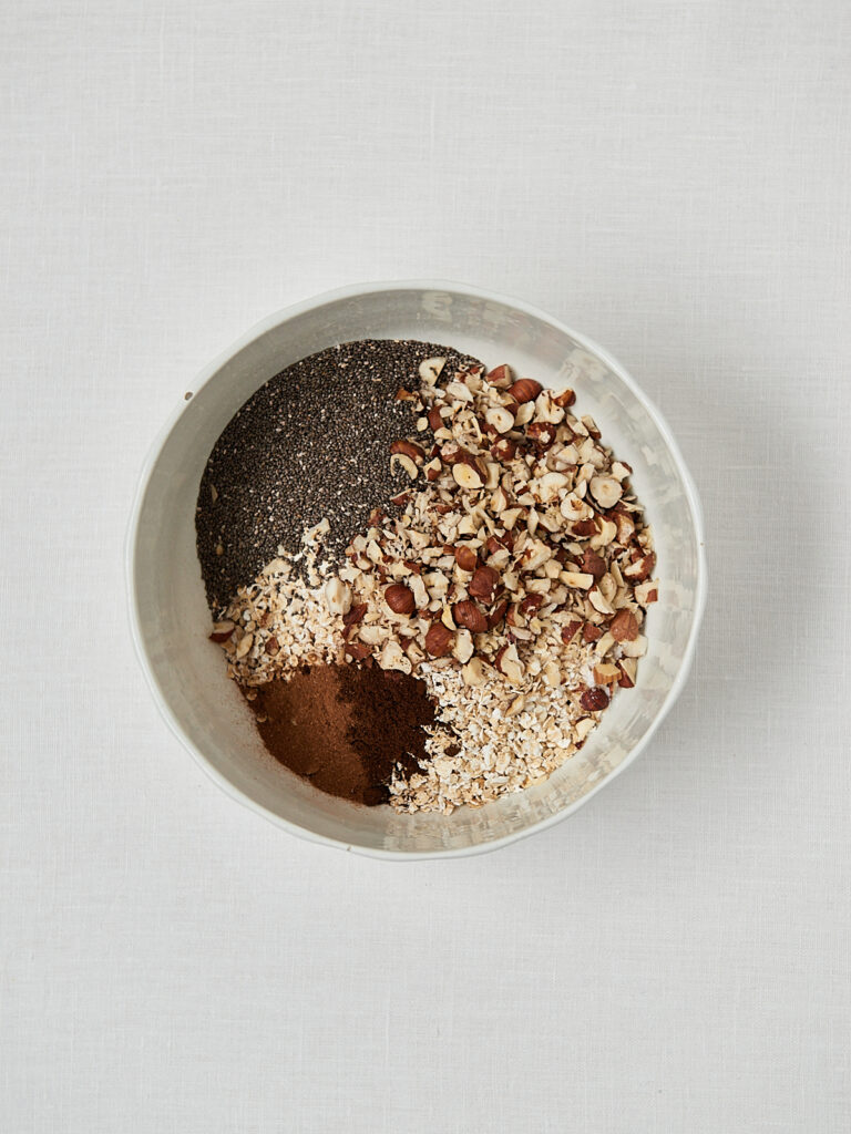 Haferflocken-Samen-Mischung mit Kakaopulver in Sch&uuml;ssel &ndash; Granola Zubereitung