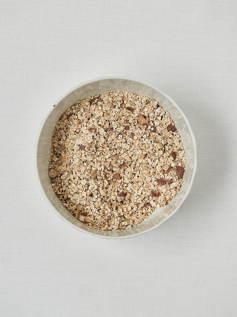 Haferflocken mit Zimt in wei&szlig;er Sch&uuml;ssel &ndash; trockene Zutaten Cherry Granola