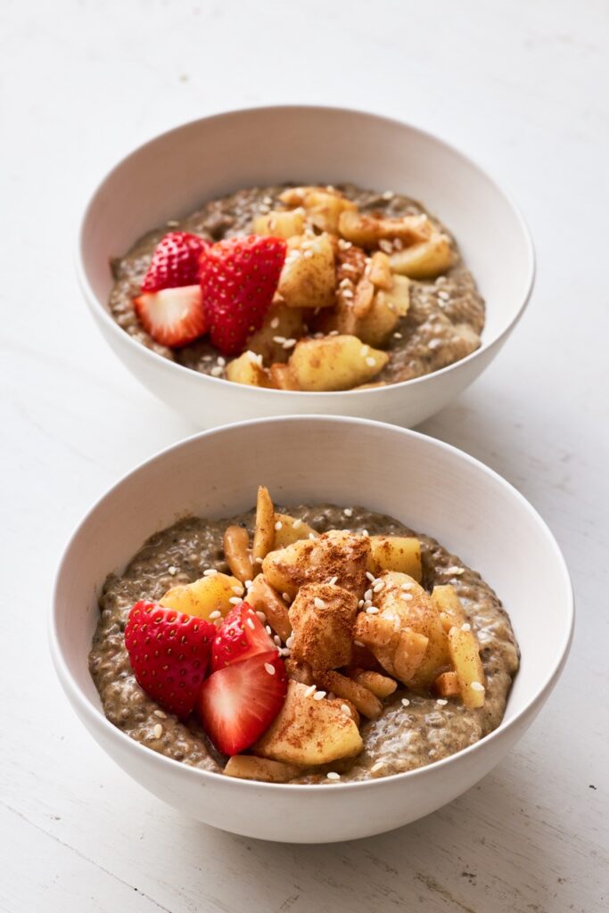 Overnight Oats mit Banane und Erdbeeren in zwei wei&szlig;en Sch&uuml;sseln &ndash; Draufsicht Fr&uuml;hst&uuml;ck Rezept