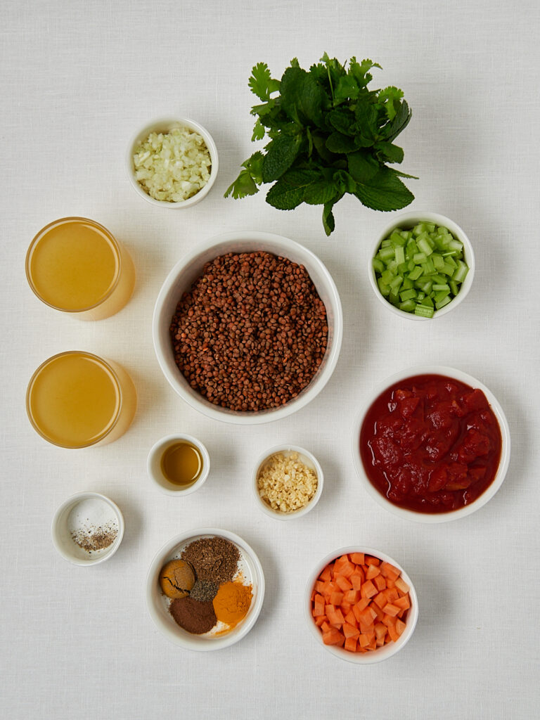 Zutaten-Flatlay marokkanische Linsensuppe – Olivenöl, Kurkuma, Kreuzkümmel, Koriander und frische Kräuter