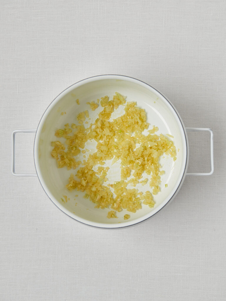 Glasig angedünstete Zwiebeln in weißer Schüssel – Basis für marokkanische Linsensuppe