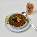 Marokkanische Linsensuppe mit Kräuter-Topping und Löffel – Studioaufnahme von oben