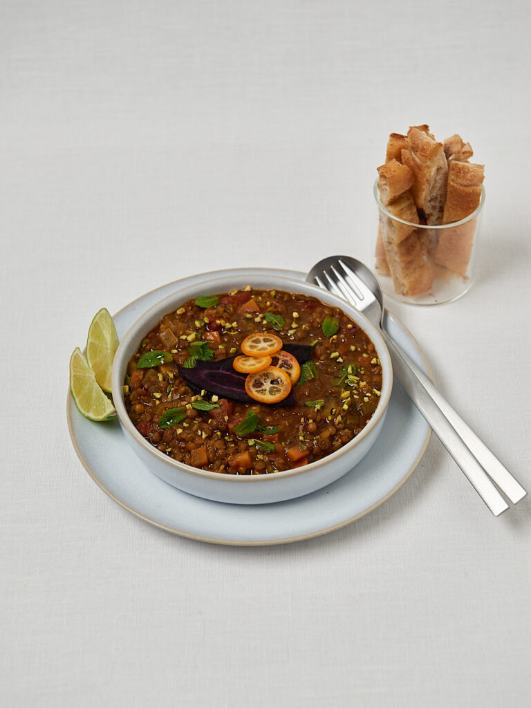 Marokkanische Linsensuppe mit Kräuter-Topping und Löffel – Studioaufnahme von oben
