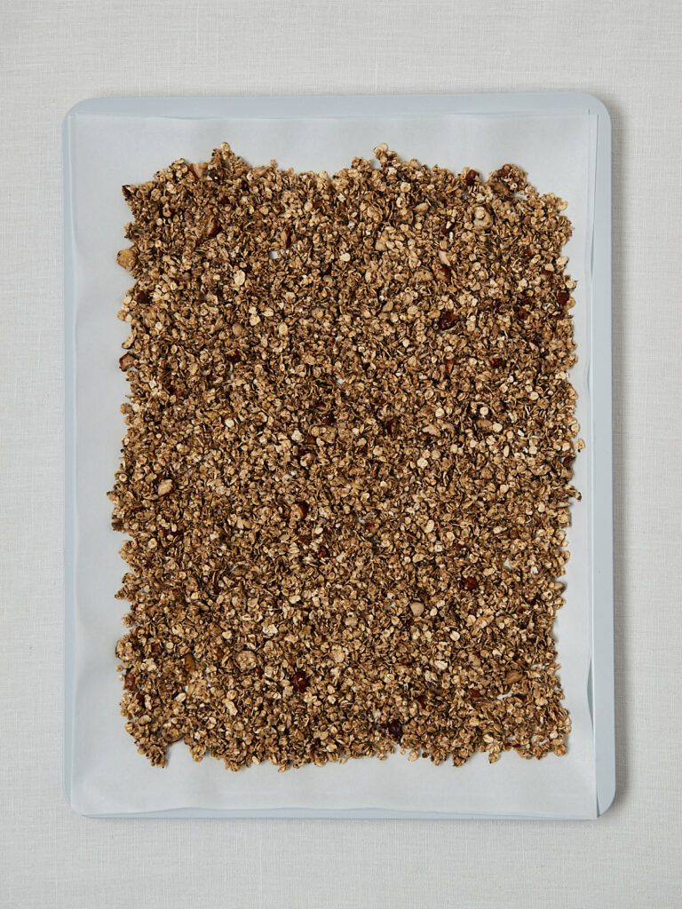 Gebackenes Granola auf Backpapier &ndash; Draufsicht nach dem Backen vor dem Abk&uuml;hlen