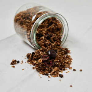 Cherry Chocolate Granola aus wei&szlig;er T&uuml;te auf hellem Untergrund &ndash; knuspriges Fr&uuml;hst&uuml;cksgranola