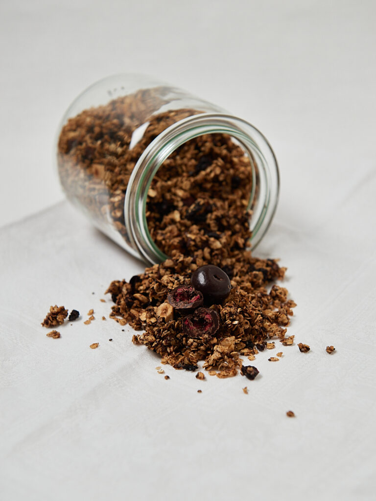 Cherry Chocolate Granola aus wei&szlig;er T&uuml;te auf hellem Untergrund &ndash; knuspriges Fr&uuml;hst&uuml;cksgranola