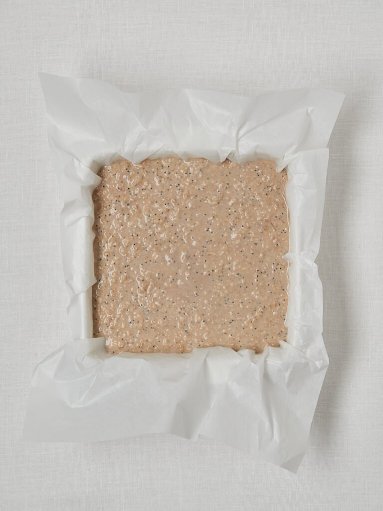 Roher Baked Oats Teig in Backpapier-Form vor dem Backen – helle Masse Draufsicht