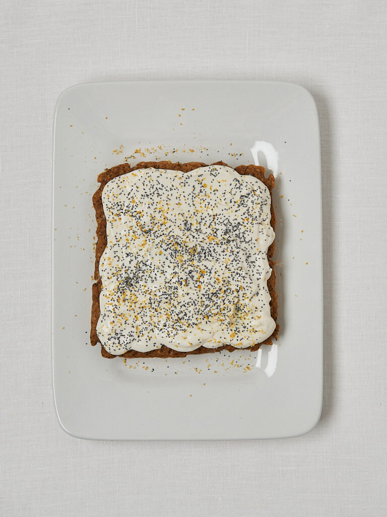 Baked Oats mit weißem Topping frisch bestrichen – Overhead Shot vor dem Garnieren