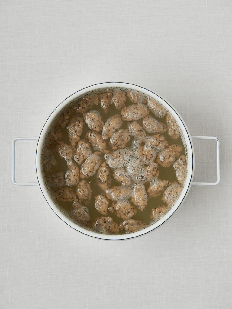 Haferflocken Gnocchi in weißer Schüssel mit Wasser – Zubereitungsschritt Overhead
