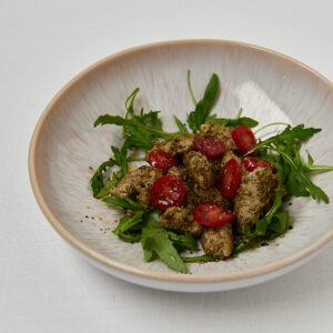 2-Zutaten Gnocchi mit Tomaten und Rucola auf hellem Teller – Overhead Shot