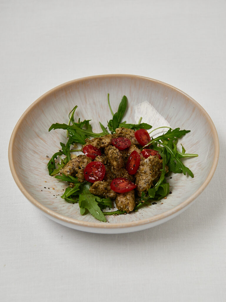 Gnocchi Salat mit Kirschtomaten, Rucola und Pesto auf Keramikteller – Draufsicht