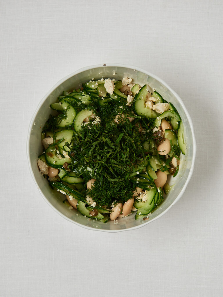 Gurken Bohnensalat mit frischem Dill in wei&szlig;er Sch&uuml;ssel &ndash; Zubereitungsschritt vor dem Vermengen