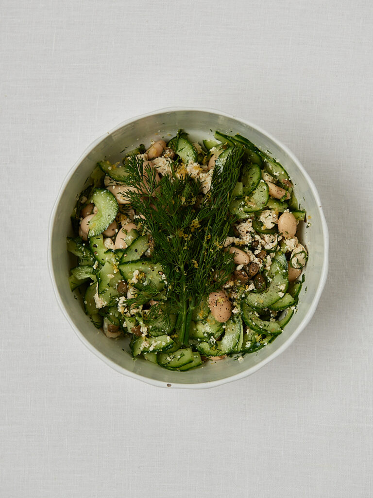 Fertiger Gurken Feta Salat mit wei&szlig;en Bohnen und Kr&auml;utern in wei&szlig;er Sch&uuml;ssel &ndash; Draufsicht