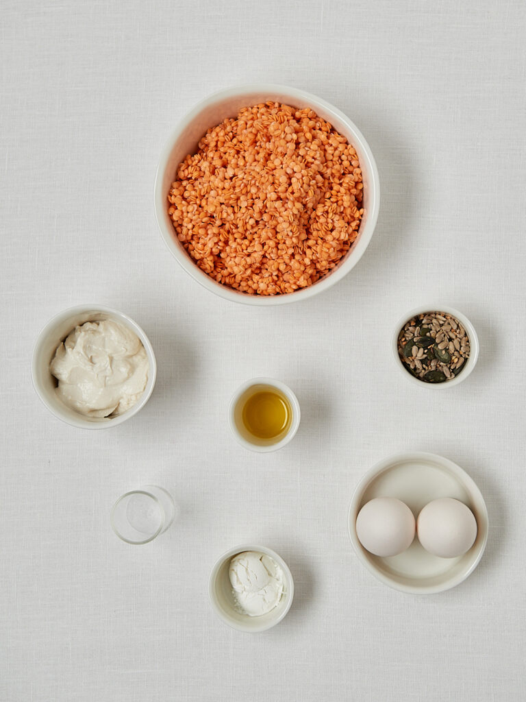 Zutaten Linsenbrot Flatlay &ndash; rote Linsen, Joghurt, Eier und Oliven&ouml;l in Sch&auml;lchen auf hellem Untergrund