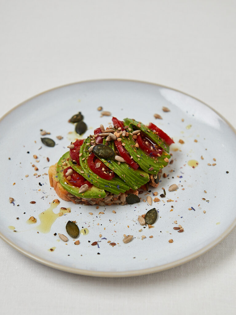 Linsenbrot Scheibe mit Avocado, K&uuml;rbiskernen und Oliven&ouml;l &ndash; Overhead Shot Studioaufnahme