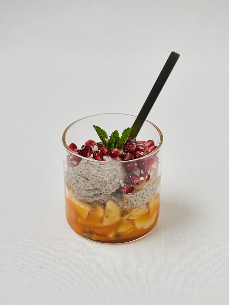 Chia Pudding mit Mango, Granatapfelkernen und Minze im Glas mit schwarzem L&ouml;ffel &ndash; gesundes Meal Prep Fr&uuml;hst&uuml;ck