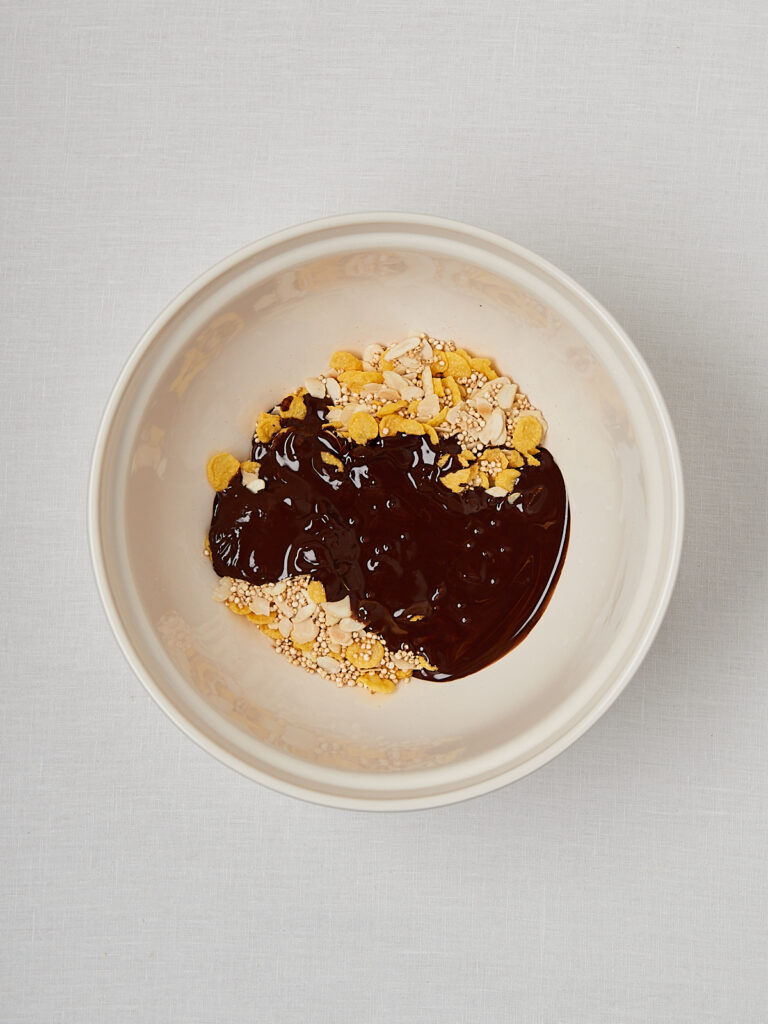 Schokocrossies Teig in Sch&uuml;ssel mit Cornflakes und geschmolzener Dattelschokolade