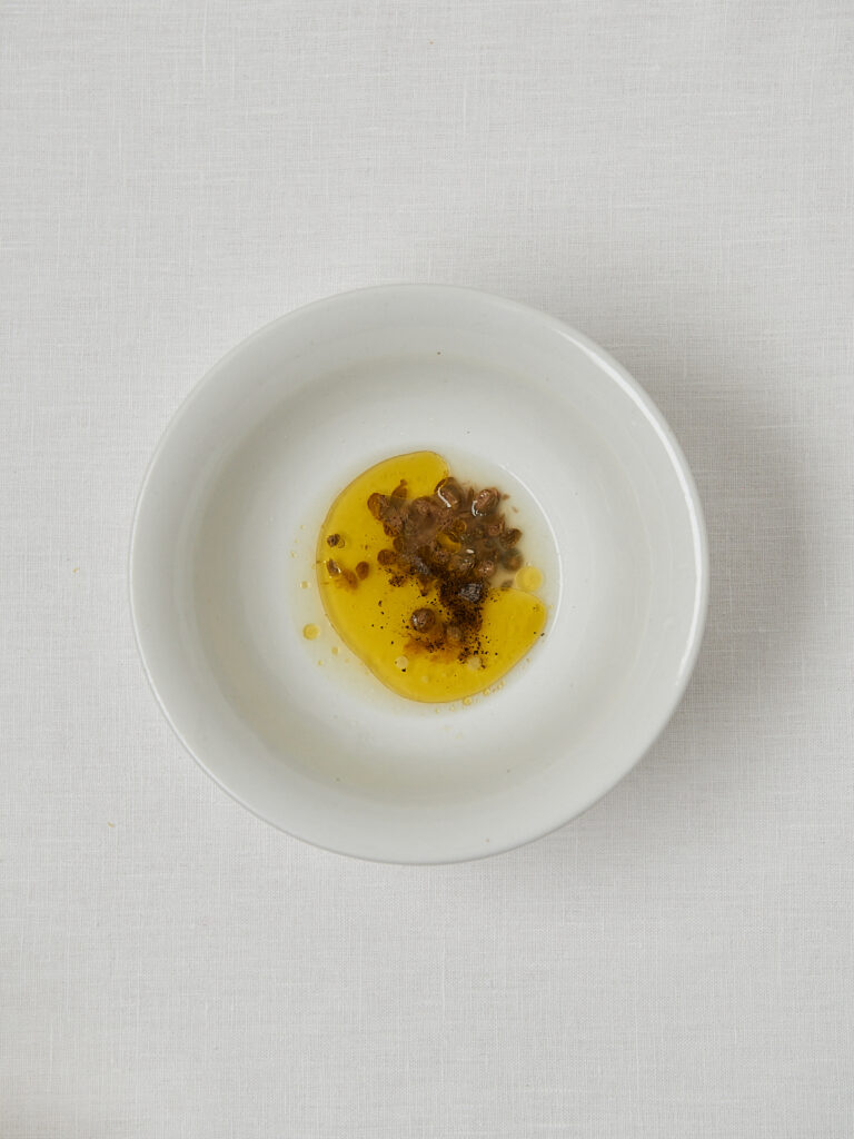 Kr&auml;uter Dressing mit Oliven&ouml;l und Essig in wei&szlig;em Teller &ndash; Zubereitungsschritt Salat