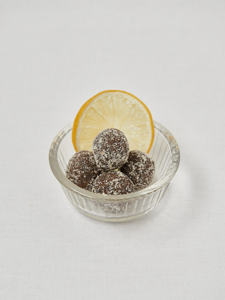 Zitronen Energy Balls in runder Glassch&uuml;ssel mit Zitrone &ndash; Draufsicht