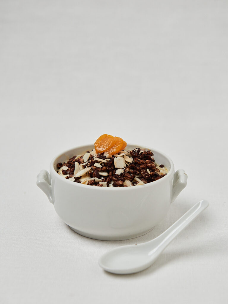 Rice Puff Cereal mit Schokolade in wei&szlig;er Sch&uuml;ssel mit Mandarine &ndash; seitliche Studioaufnahme