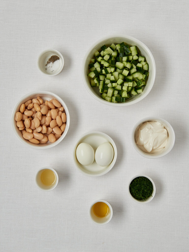 Zutaten-Flatlay Gurken Dill Bowl – weiße Bohnen, Gurke, Eier, Joghurt und Olivenöl Overhead