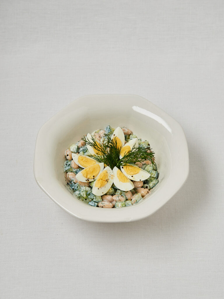Gurken Joghurt Bowl mit halbierten Eiern auf wei&szlig;em Teller &ndash; Draufsicht