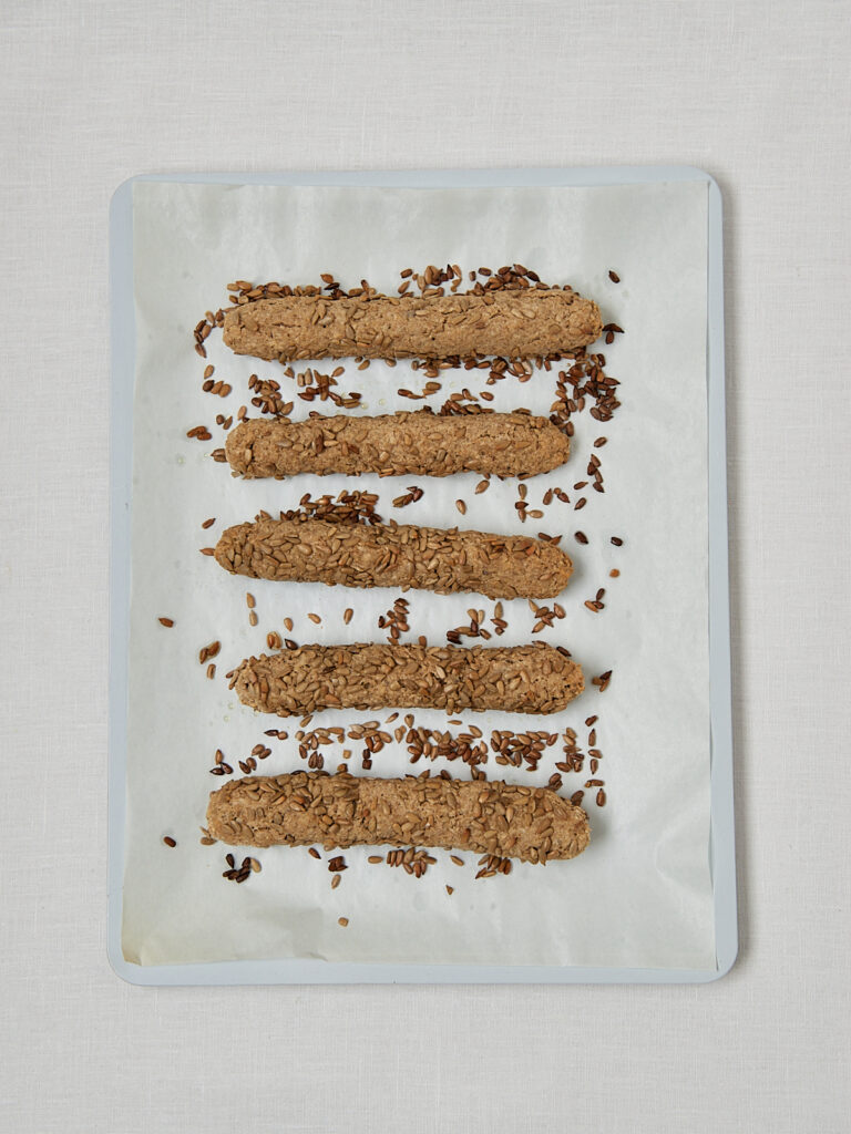 Fitnesstangen mit Sesam auf Backblech nach dem Backen &ndash; Overhead Shot