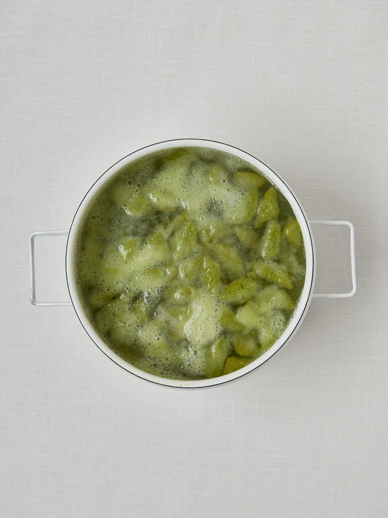 Erbsen im Kochwasser in wei&szlig;em Topf &ndash; Zubereitungsschritt Erbsennudeln Rezept