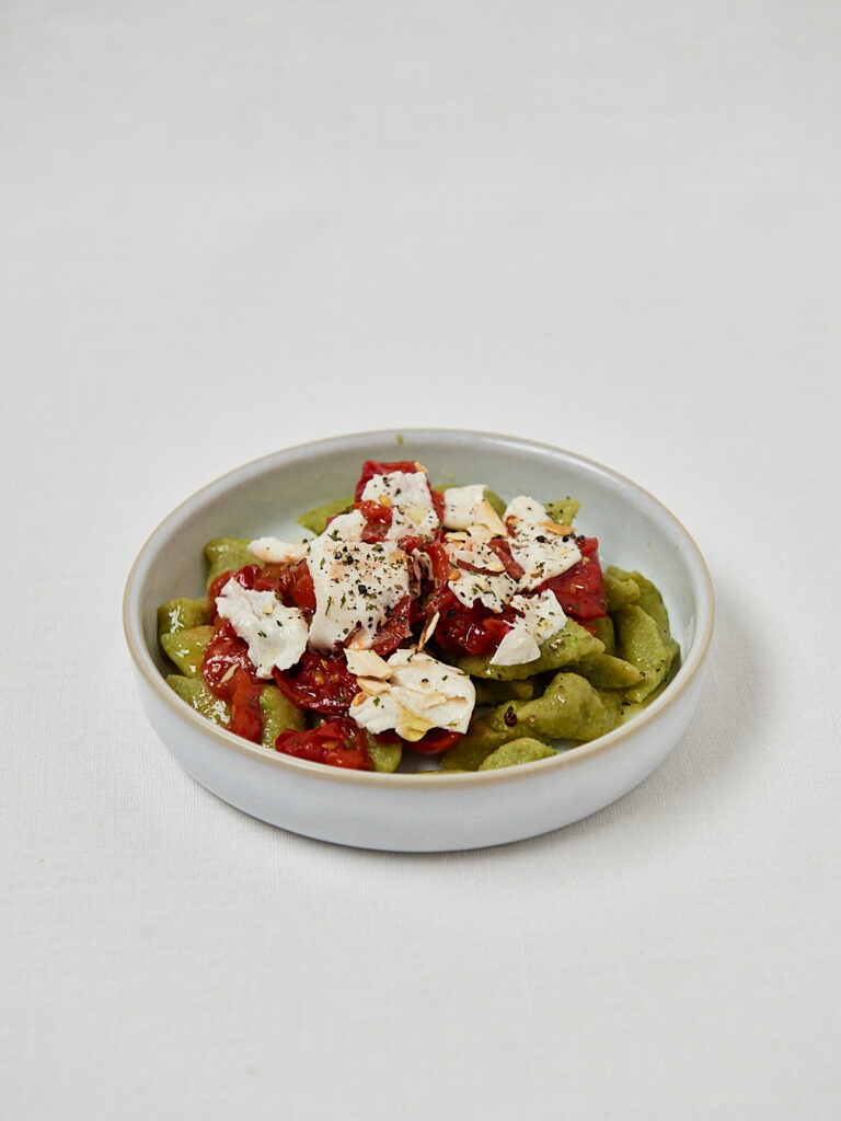 Gr&uuml;ne Gnocchi aus Erbsen mit Tomatensauce und Mozzarella &ndash; Draufsicht Studioaufnahme