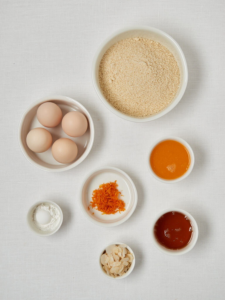 Zutaten-Flatlay Orange Almond Muffins &ndash; Eier, Mandelmehl, Honig und Orangenabrieb