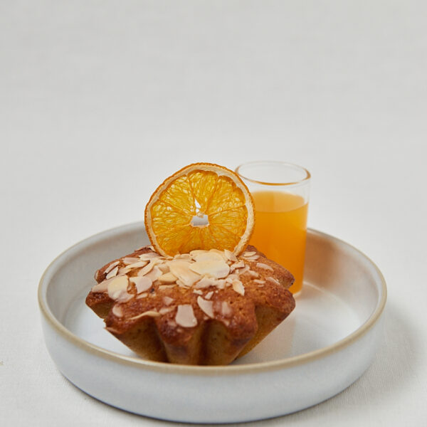 Orange Almond Muffin mit Mandelblättchen und frischem Orangensaft auf Teller
