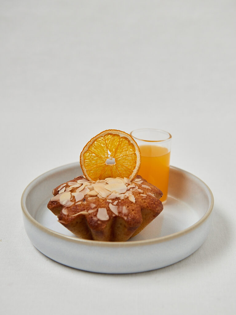 Orange Almond Muffin mit Mandelbl&auml;ttchen und frischem Orangensaft auf Teller