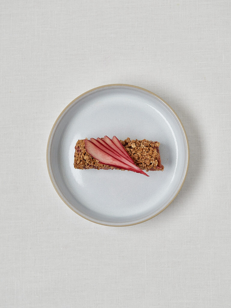 Einzelne Rhabarber Crumble Bar auf grauem Teller &ndash; minimalistischer Studioshot