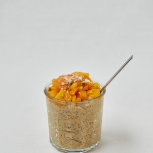 Tropical Chia Skyr Pudding mit Mango-Topping und Löffel – seitliche Studioaufnahme
