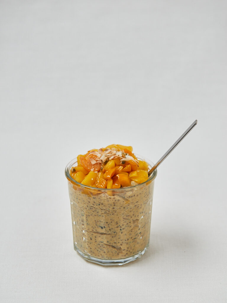 Tropical Chia Skyr Pudding mit Mango-Topping und Löffel – seitliche Studioaufnahme
