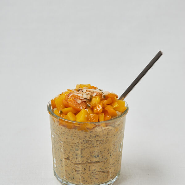 Mango Chia Pudding mit Passionsfrucht und Kokosraspeln mit Löffel – tropisches High Protein Frühstück